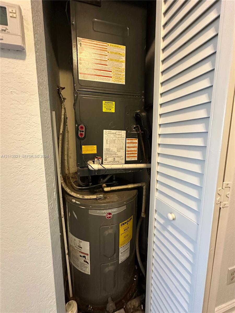 Utility closet featuring a dedicated HVAC air handler and a vertical water heater enclosed behind a white louvered door