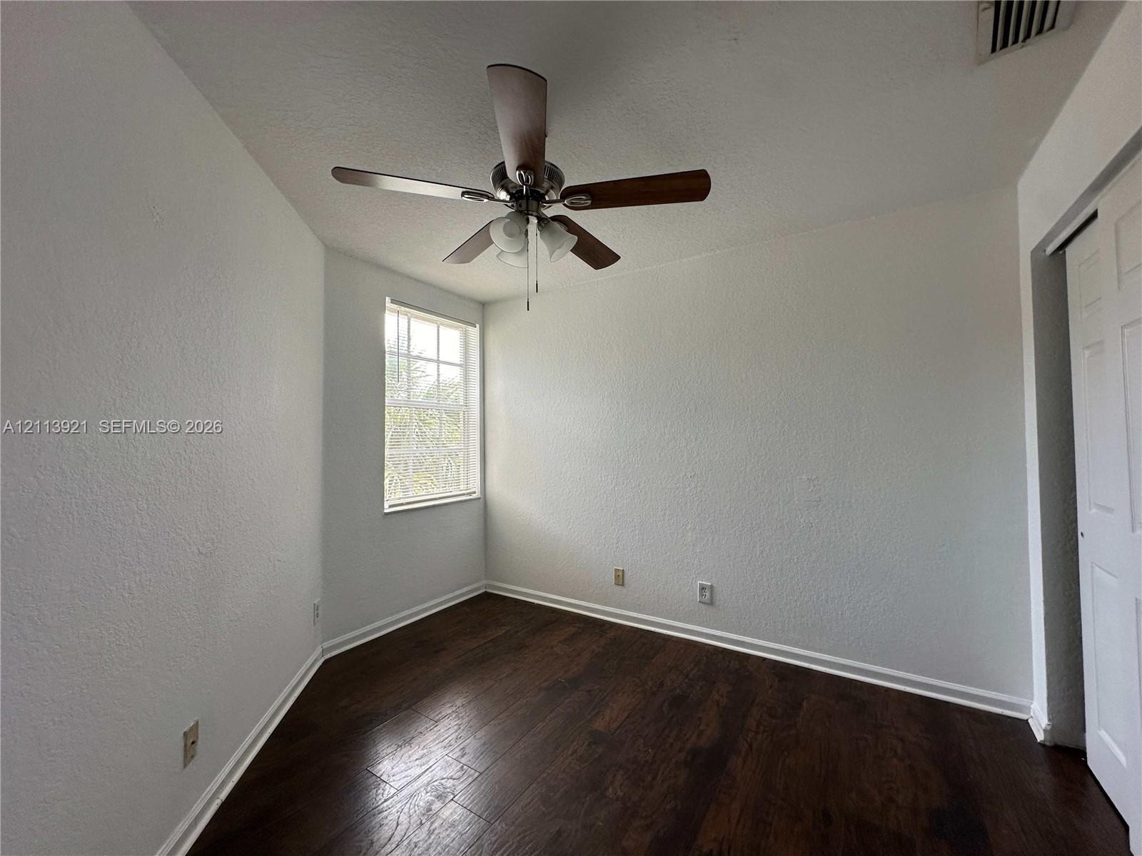 Wood-finish flooring, multi-pane window, ceiling fan with integrated light fixture, and paneled closet door