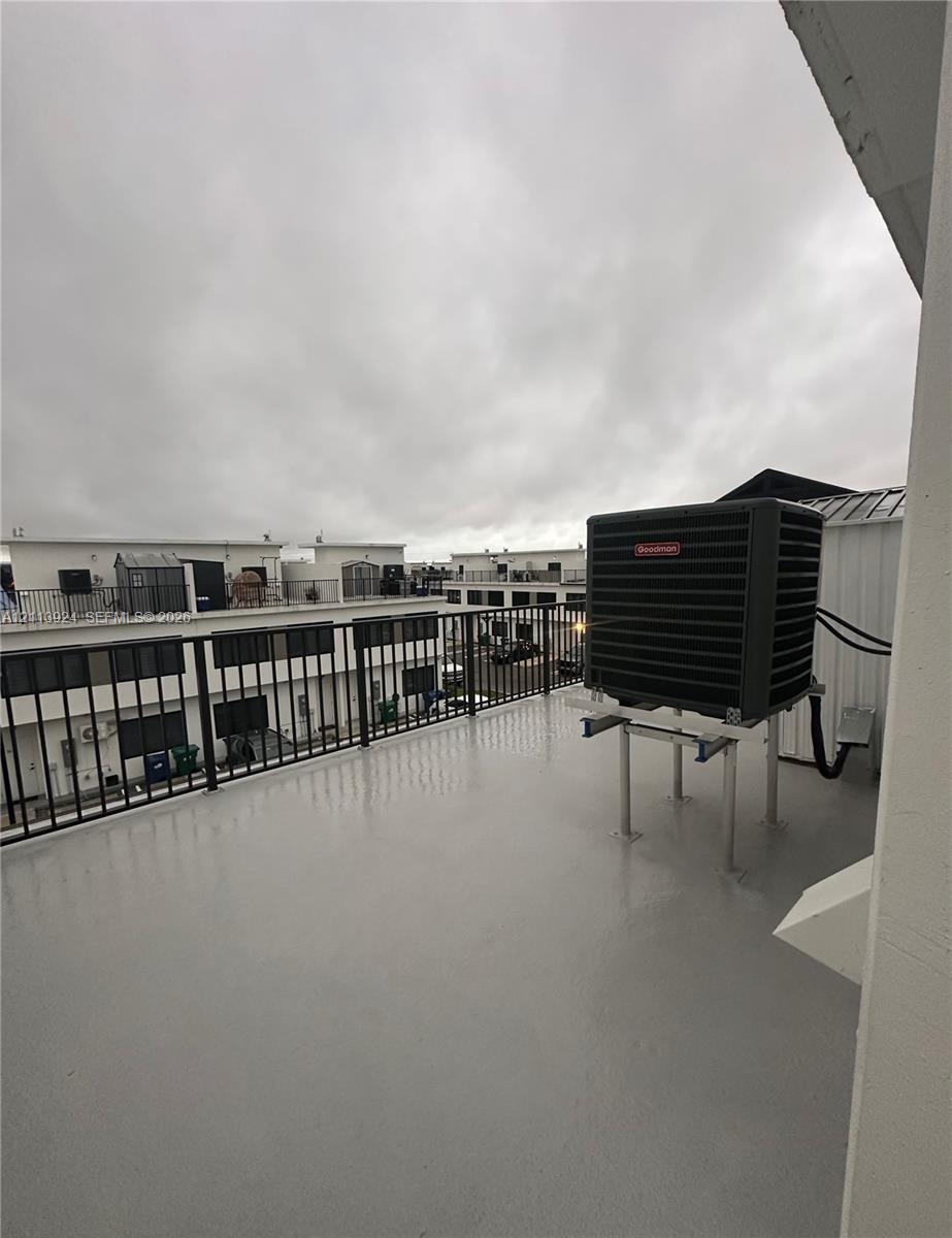 Rooftop terrace featuring a smooth-finish deck, black metal railing, and a mounted HVAC unit