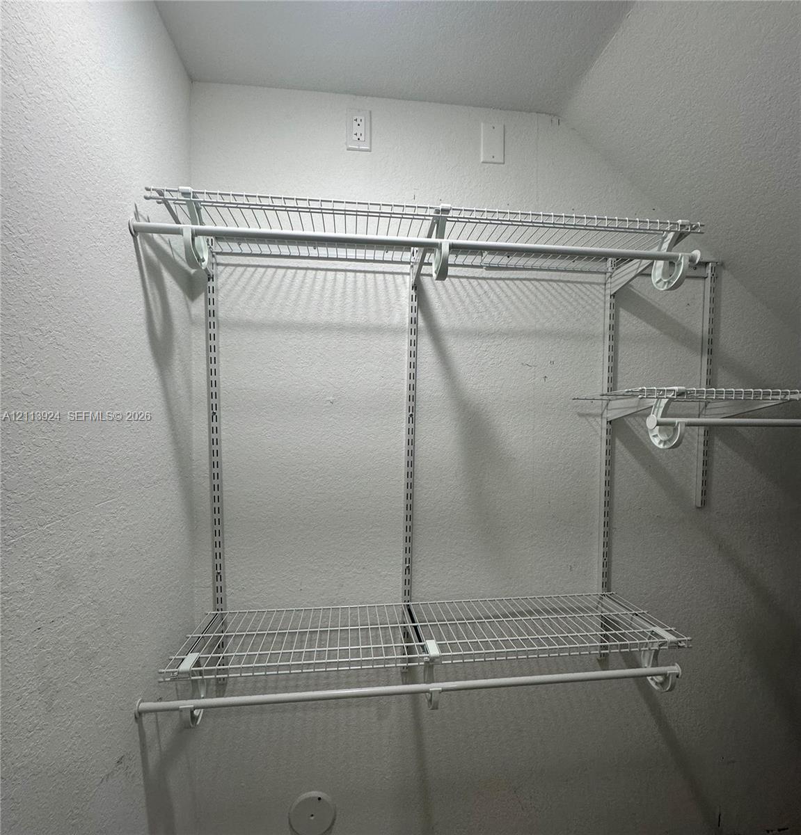 Walk-in storage space featuring adjustable white wire shelving and dual hanging rods