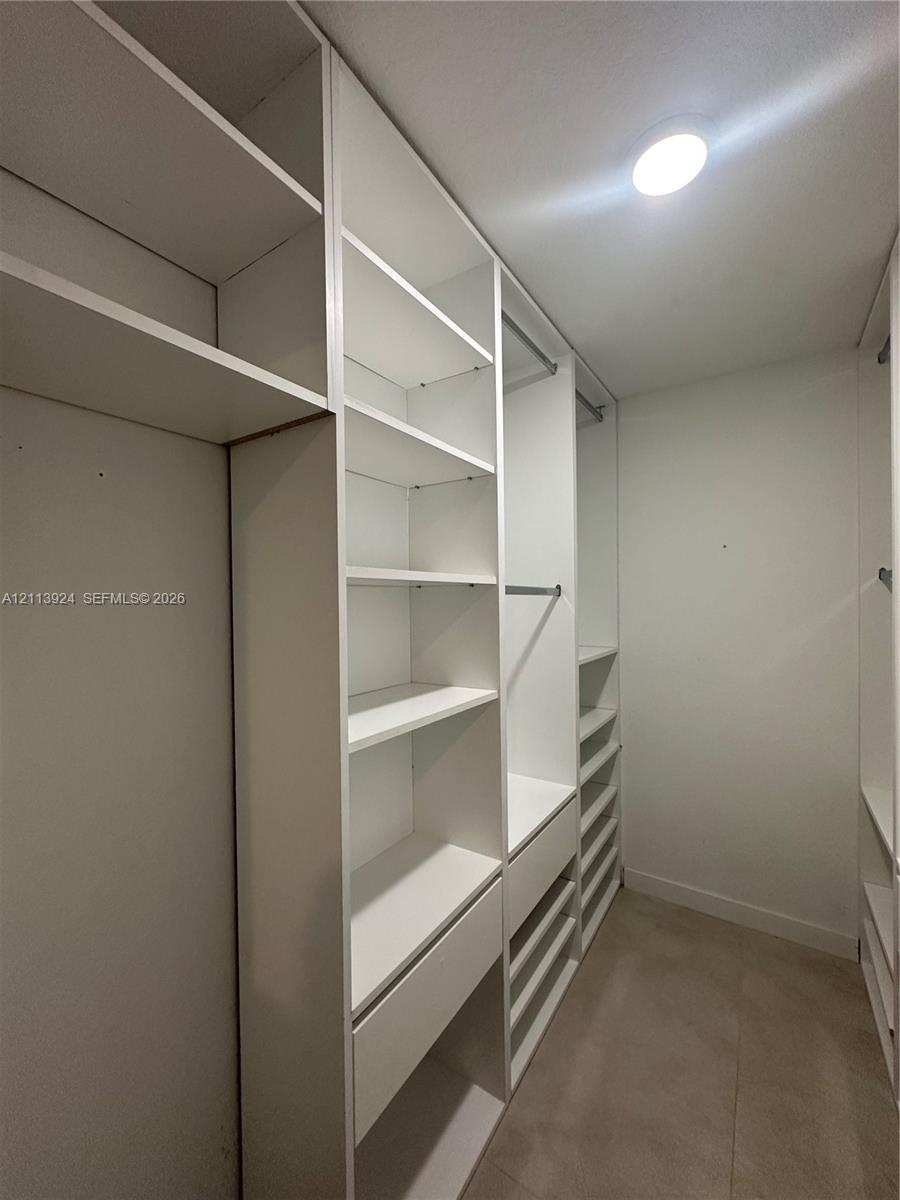 Custom built-in closet organization system featuring white shelving, integrated drawers, and metal hanging rods