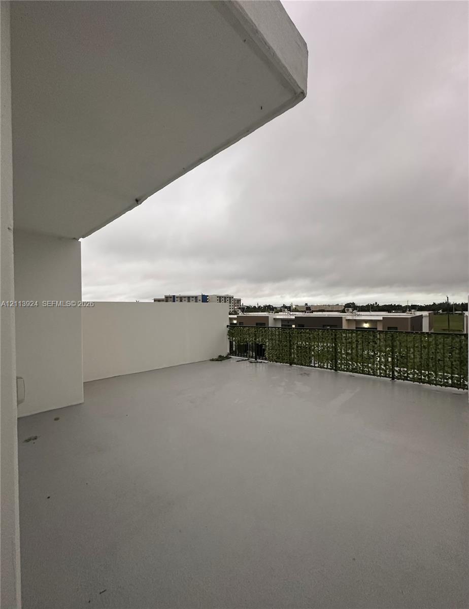 Covered balcony featuring smooth-surface flooring, high solid-panel perimeter walls, and a decorative screen railing