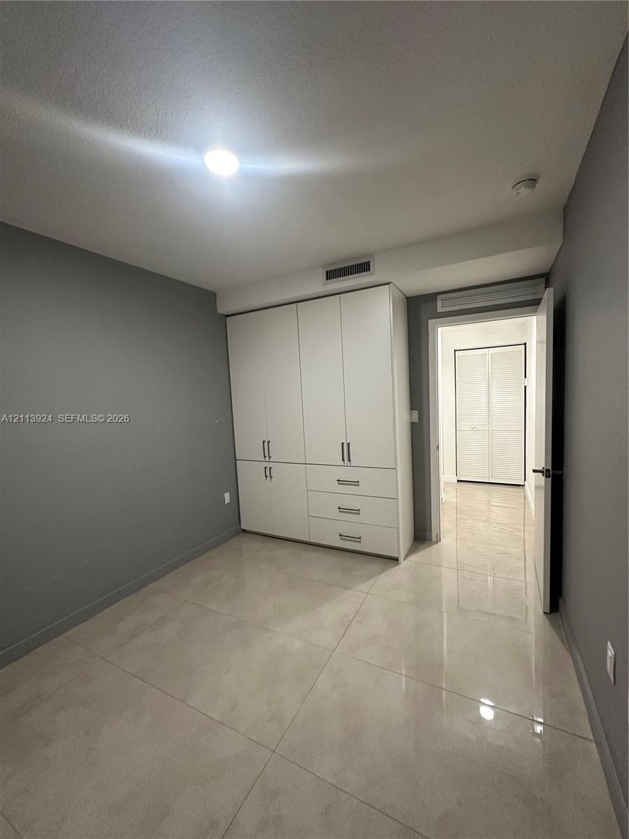 Large-format tile flooring, built-in floor-to-ceiling white cabinetry with integrated drawer storage, and neutral wall tones