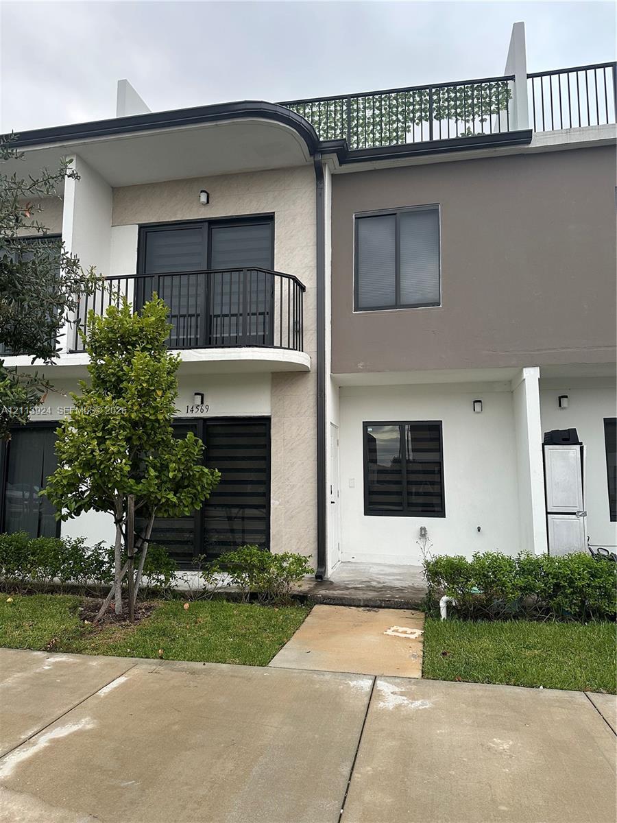 Exterior facade featuring a second-story balcony with metal railings and a private rooftop terrace