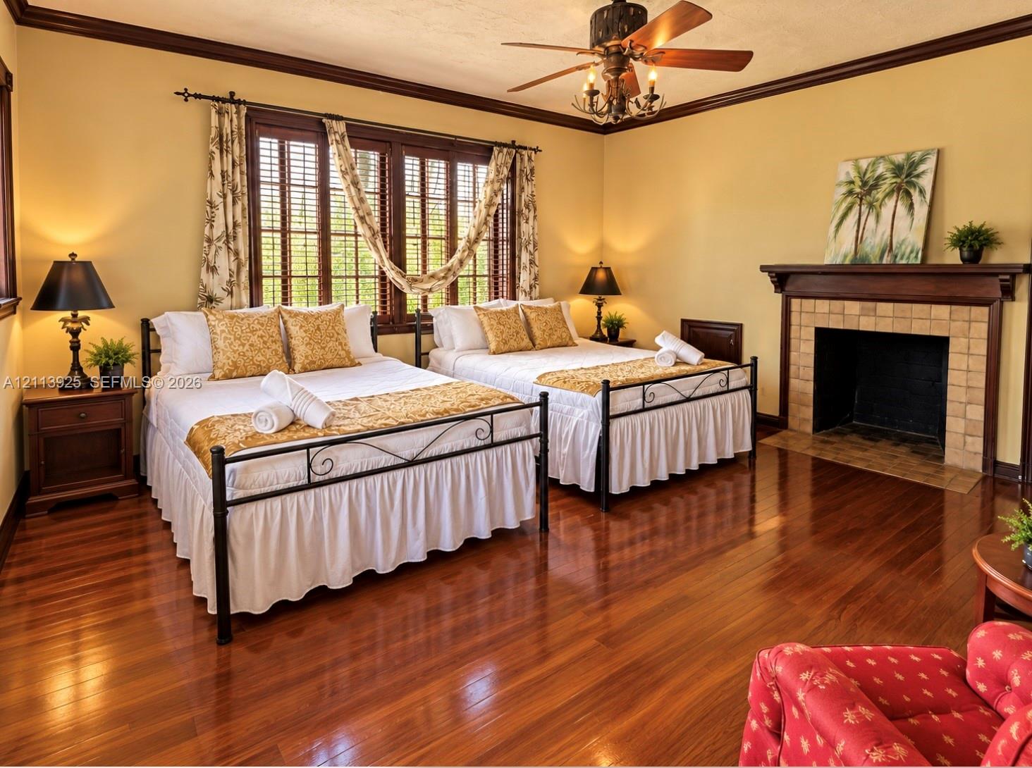 Wood-finish flooring, fireplace with a tile surround and wood mantel, multi-pane windows with louvered shutters, crown molding, and a ceiling fan with integrated lighting
