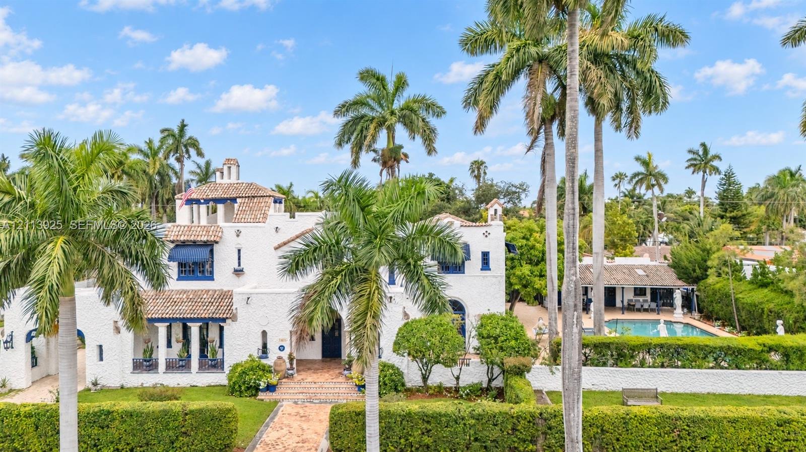 Mediterranean-style estate featuring a textured stucco exterior, clay tile roof, covered loggia, swimming pool, and gated entrance