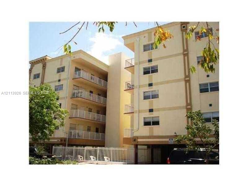 Multi-story stucco exterior featuring stacked private balconies with metal railings and under-building parking