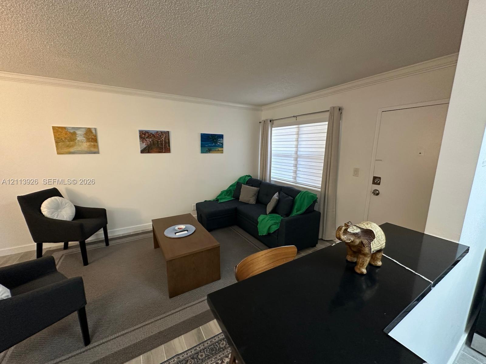 Neutral interior featuring wood-finish flooring, a solid-surface countertop with an integrated breakfast bar, and a window with horizontal blinds