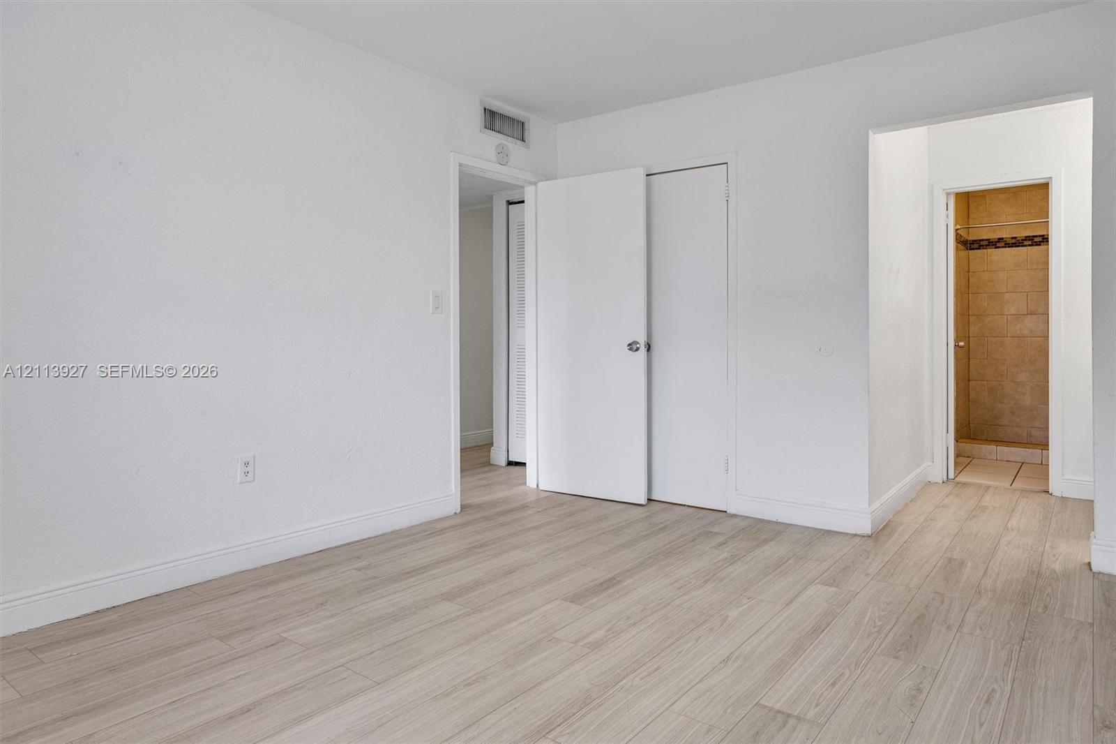 Interior space featuring wood-finish flooring, white walls, and interior swinging doors