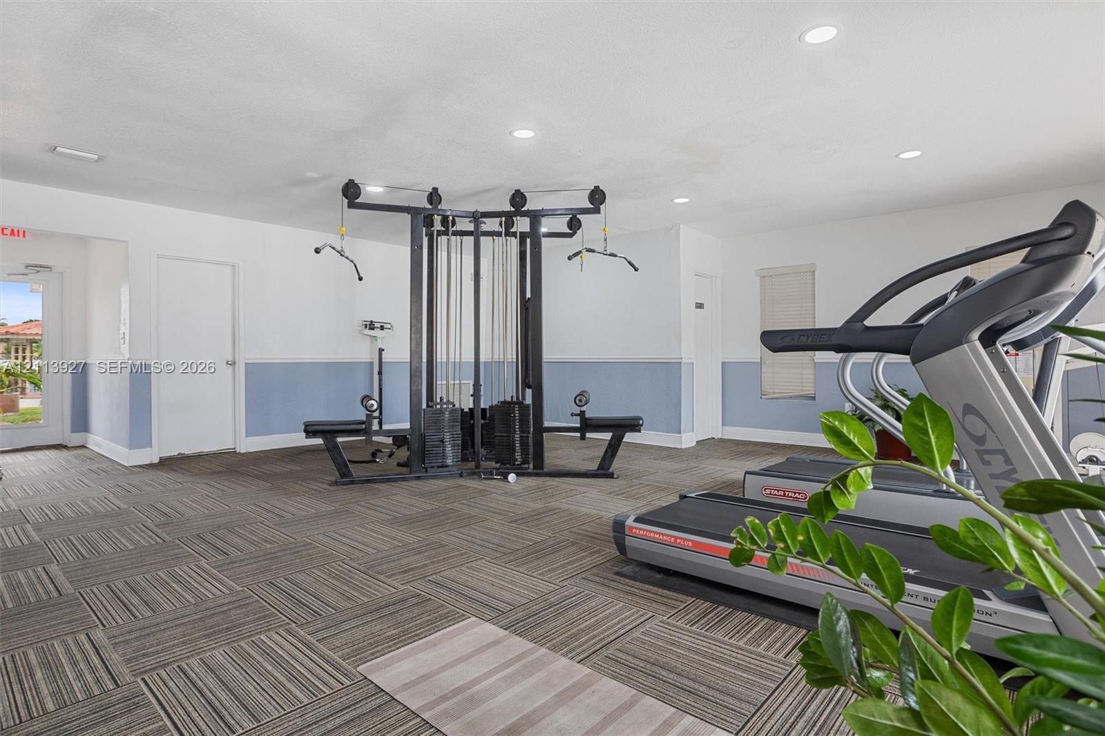 Fitness area featuring patterned tile flooring, recessed lighting, and wall-mounted blinds
