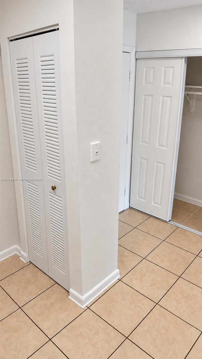 Tile flooring, bi-fold louvered closet doors, and a sliding closet door with built-in shelving