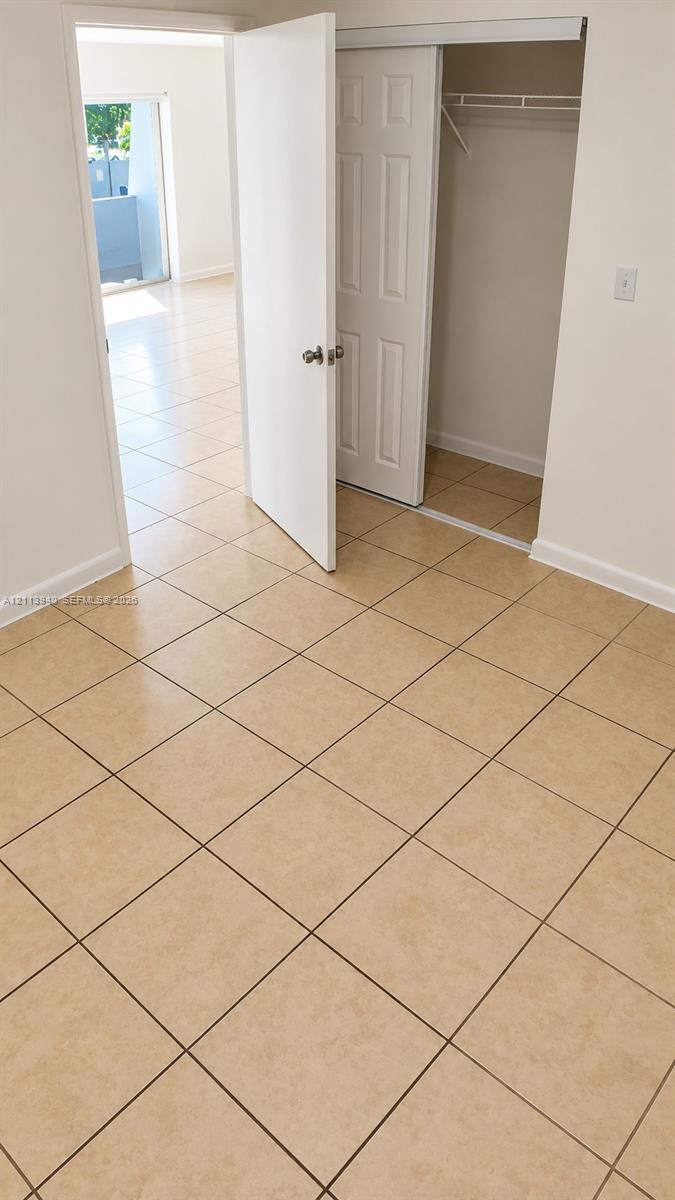 Room featuring neutral tile flooring, a closet with sliding panel doors, and a swinging interior door