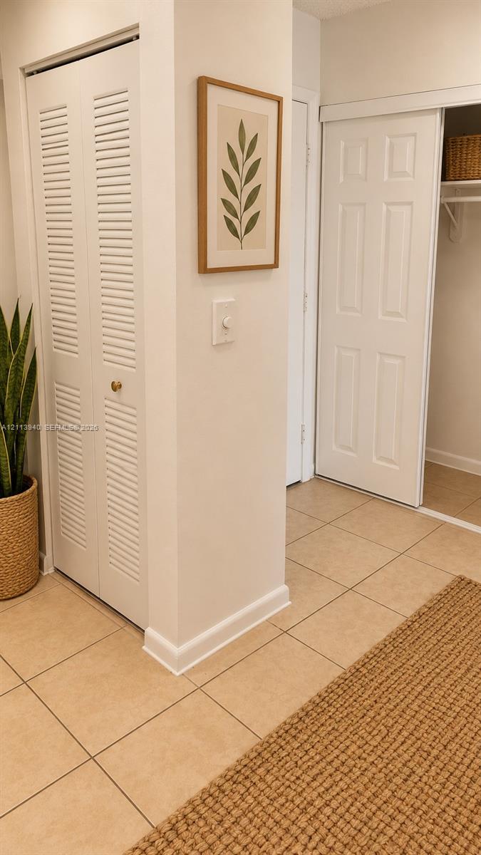 Ceramic tile flooring, bi-fold louvered closet doors, and a sliding closet door with built-in shelving