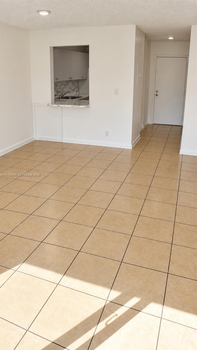 Ceramic tile flooring, pass-through opening, stone-finish countertop, recessed lighting, and solid-core entry door