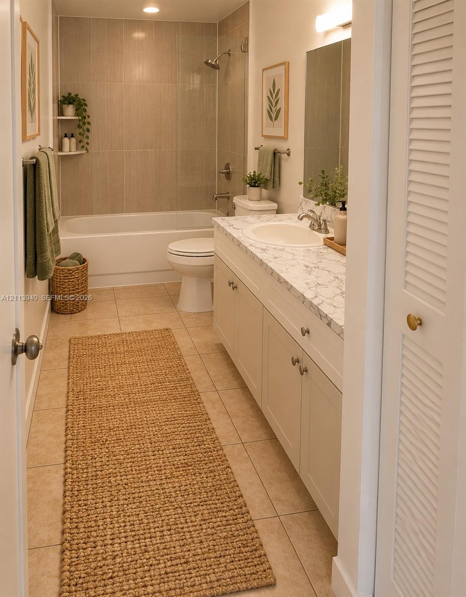 Bathroom featuring a vanity with stone-patterned countertop, under-mount sink, tile flooring, built-in recessed shelving, and a shower-tub combination with floor-to-ceiling tile surround