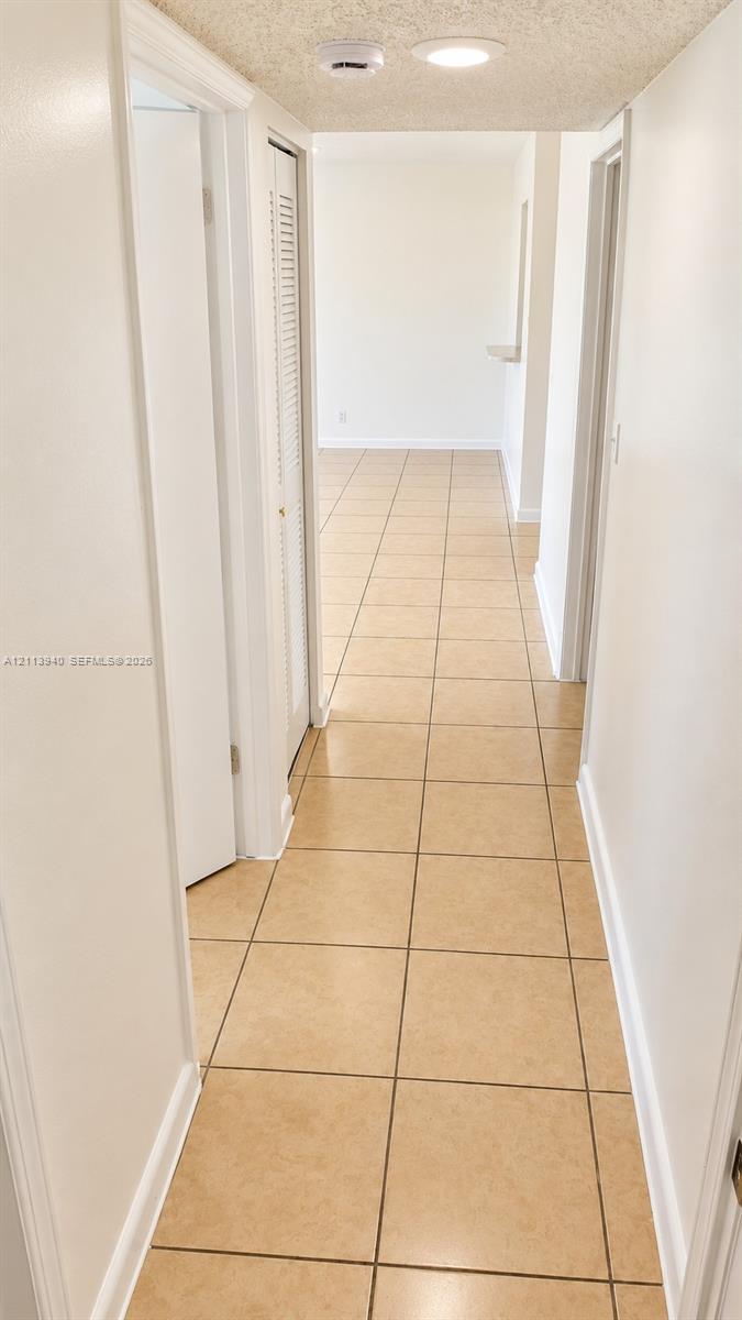 Hallway featuring neutral ceramic tile flooring, recessed lighting, and louvered closet doors