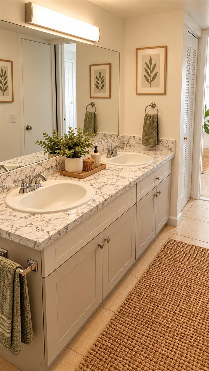 Dual-sink vanity with a patterned stone-surface countertop, integrated basin sinks, polished chrome fixtures, and a full-width vanity mirror