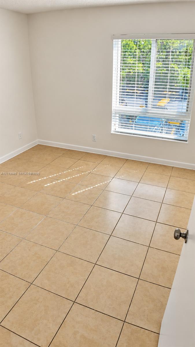 Neutral-toned tile flooring throughout with a single-pane window featuring integrated horizontal blinds