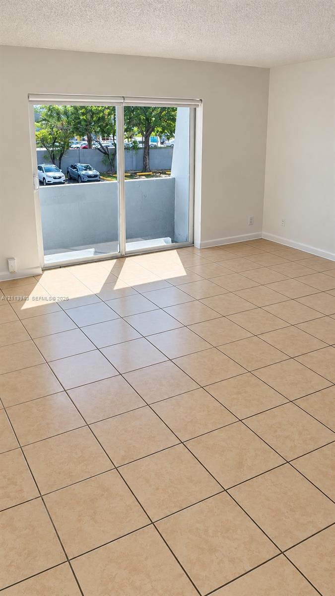 Neutral-toned ceramic tile flooring, sliding glass doors, and a private balcony with concrete wall enclosure