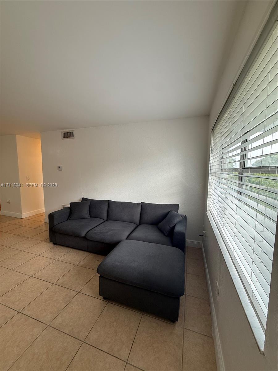 Ceramic tile flooring, neutral wall finishes, and expansive windows featuring horizontal slat blinds