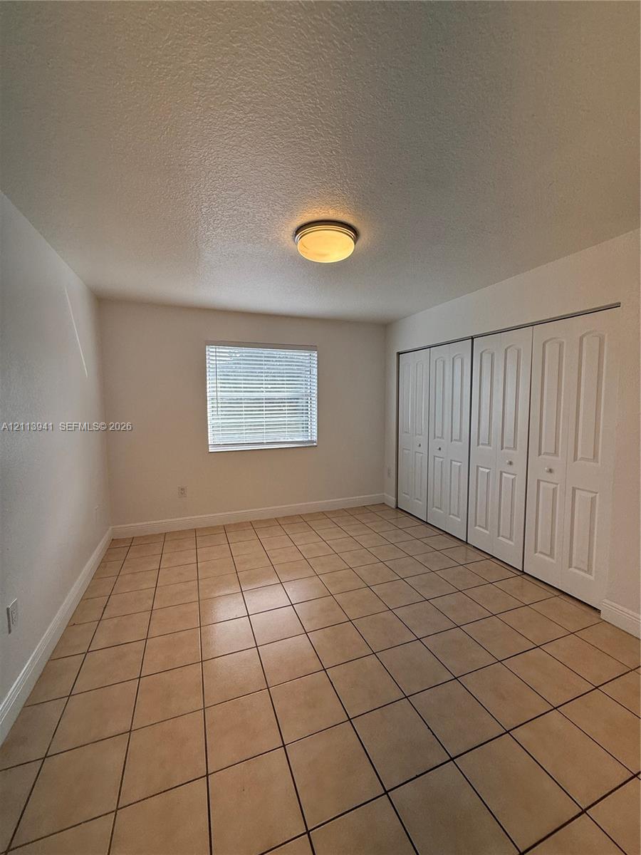 Neutral-toned tile flooring, multi-panel closet doors, and flush-mount ceiling lighting