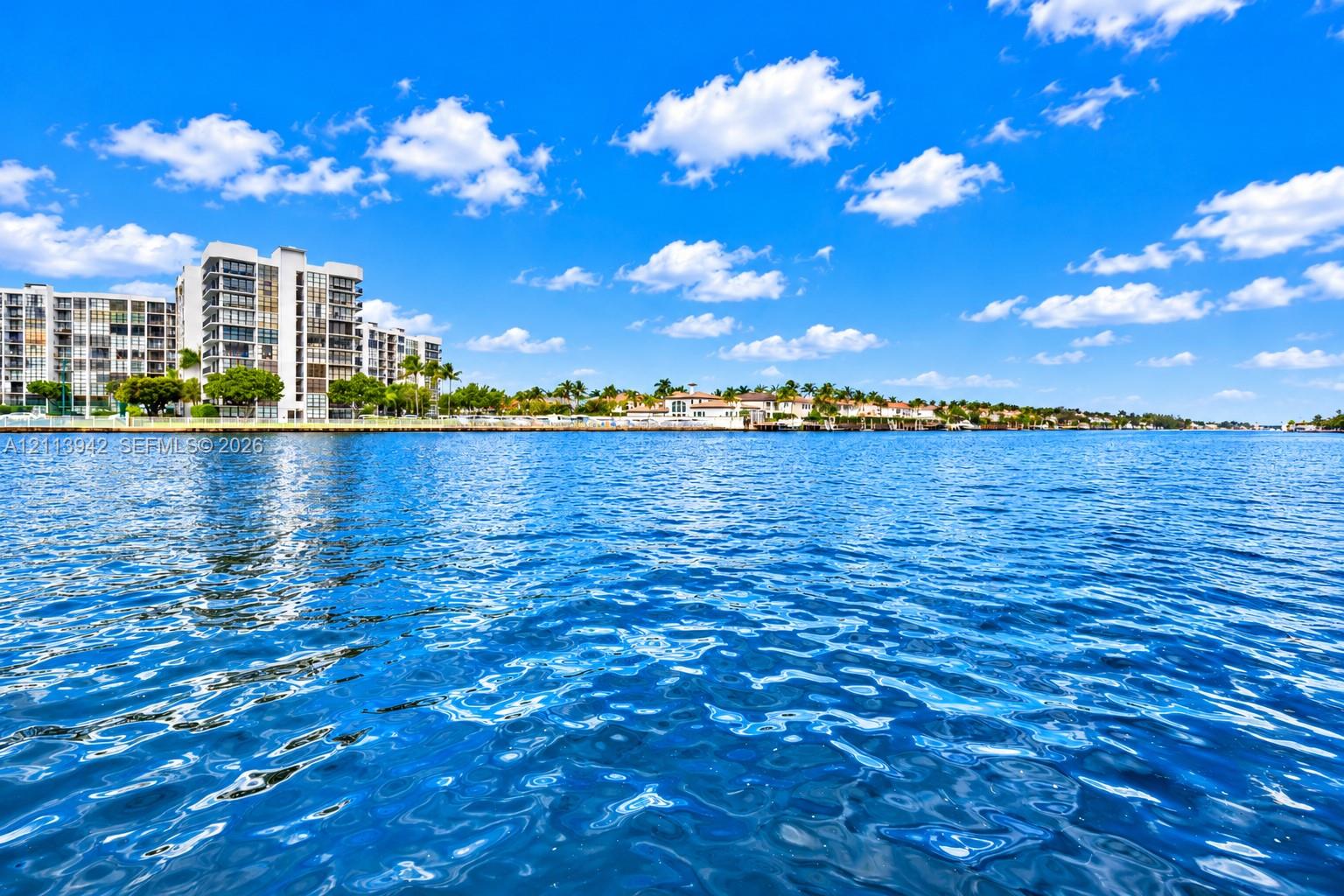 Direct waterfront setting featuring expansive water frontage, multi-story coastal architecture, and mature palm tree landscaping