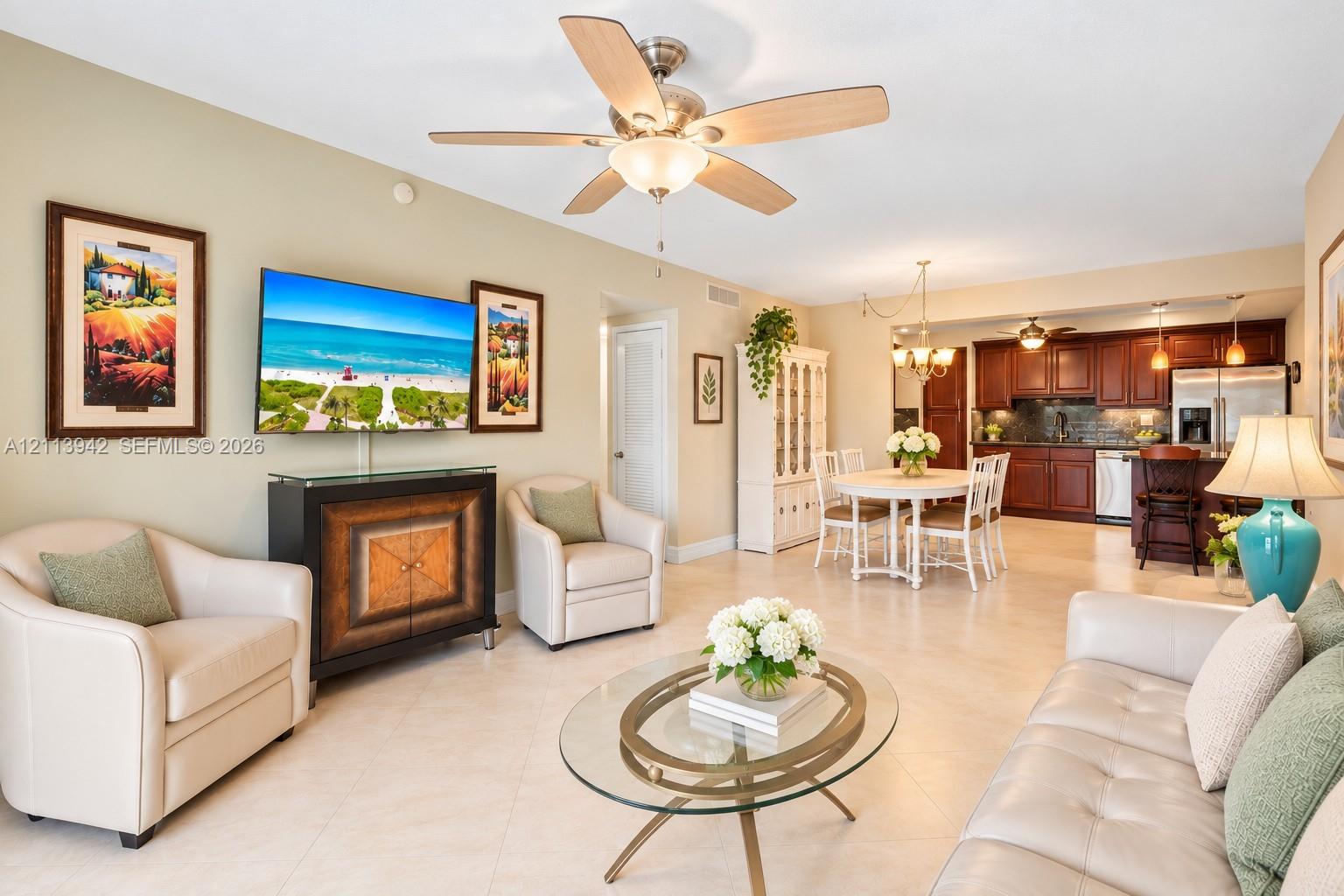 Open-concept living space featuring large-format tile flooring, recessed ceiling lighting, a multi-blade ceiling fan, and a kitchen equipped with dark wood cabinetry