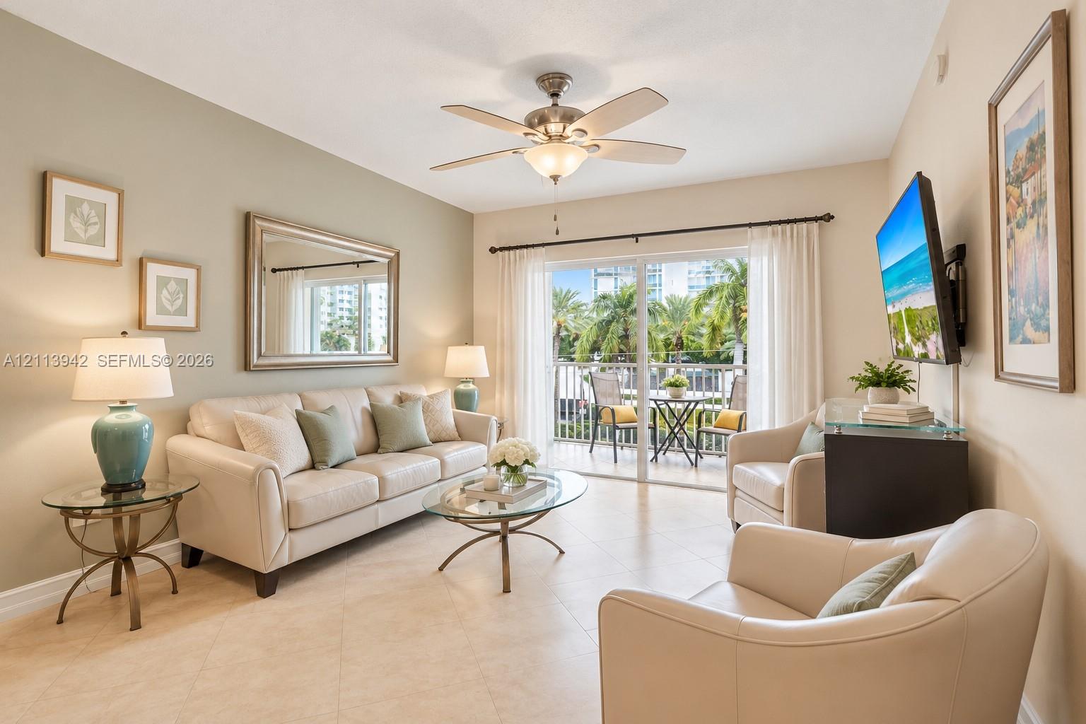 Living area featuring tile flooring, vaulted ceilings, a central ceiling fan, and sliding glass doors leading to a balcony