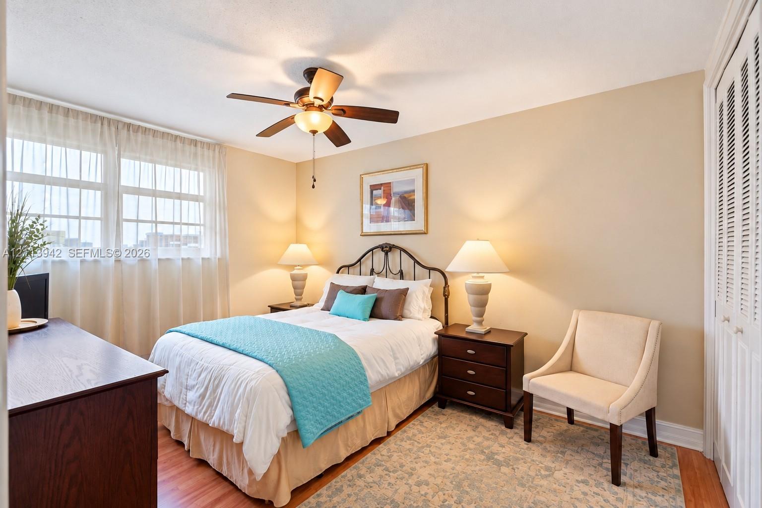 Multi-pane window, wood-finish flooring, ceiling fan with integrated lighting, and louvered double-door closet
