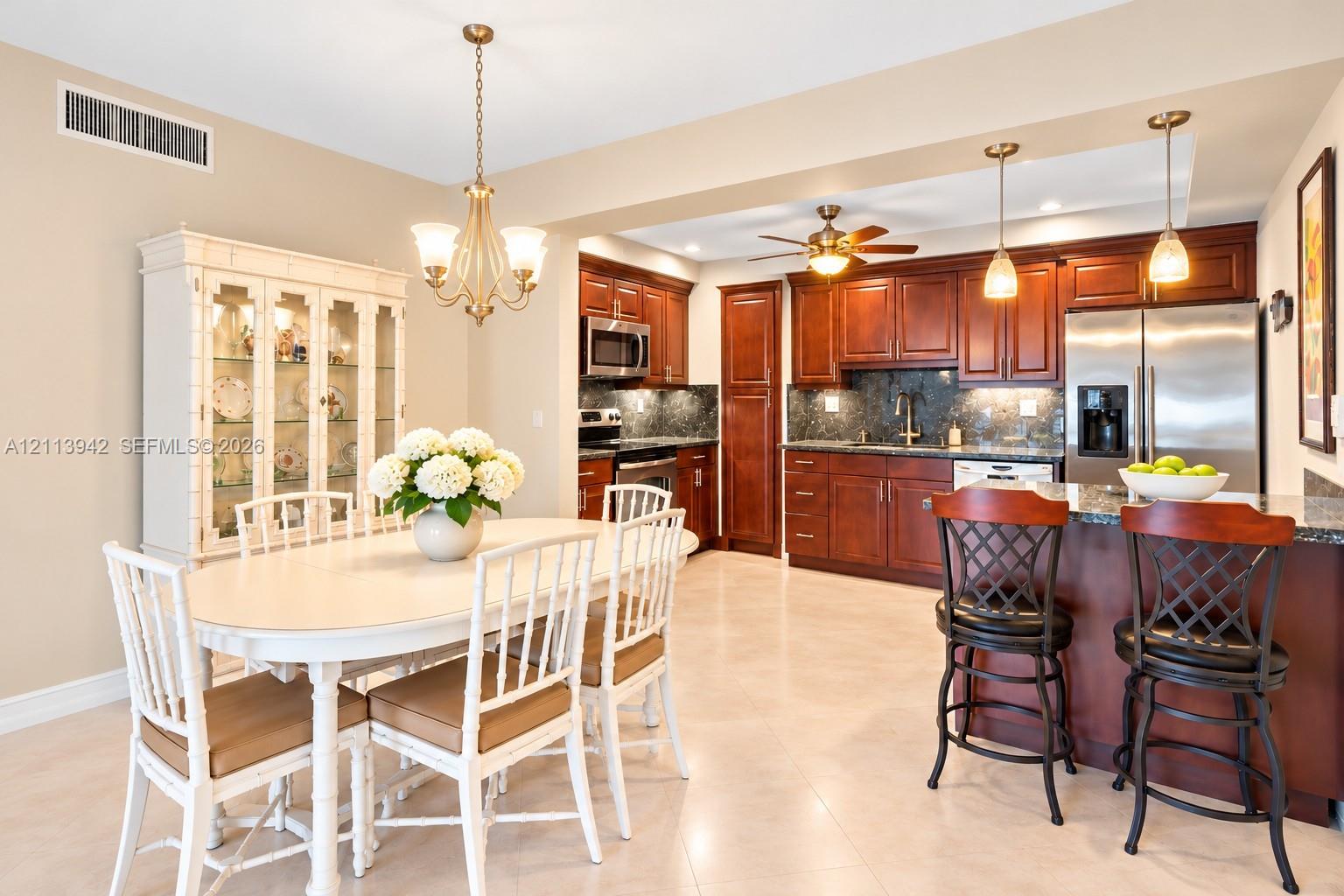 Kitchen featuring rich wood cabinetry, stone-surface countertops, stainless steel appliances, and a central island with pendant lighting