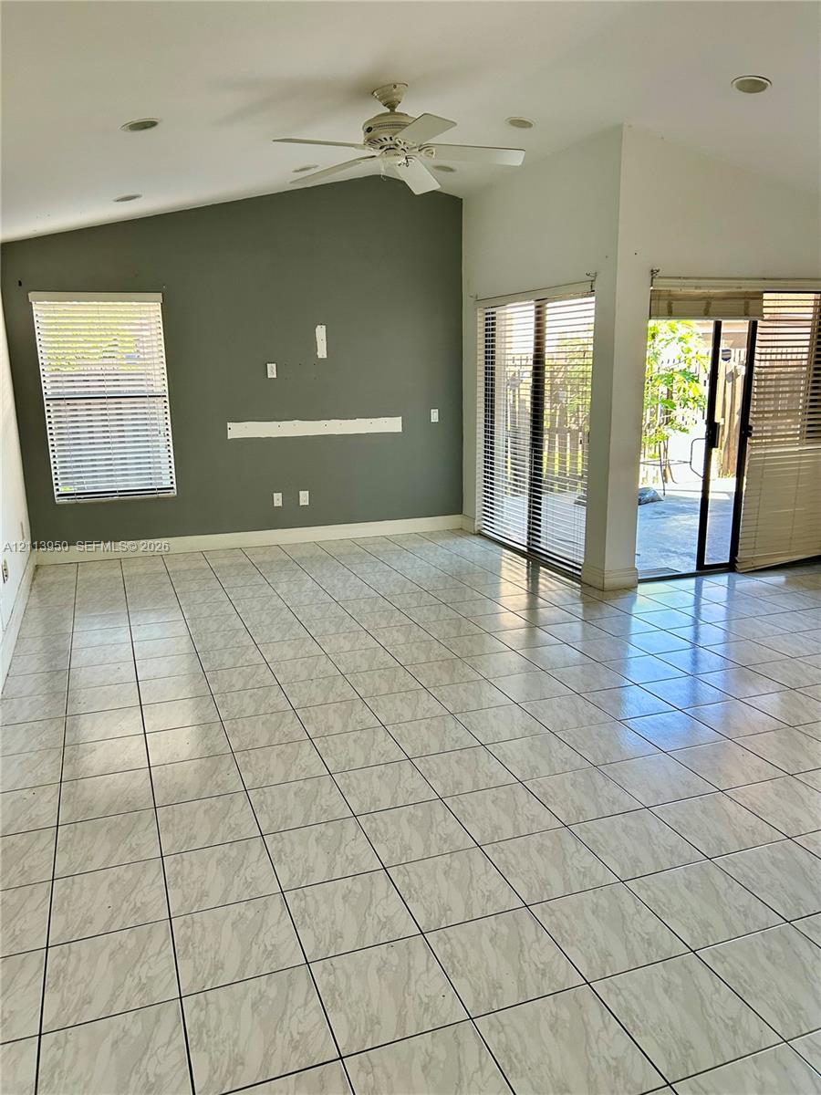 Vaulted ceiling with a central paddle fan, tile flooring, and glass sliding doors Vaulted ceiling with a central paddle fan, tile flooring, and glass sliding doors
