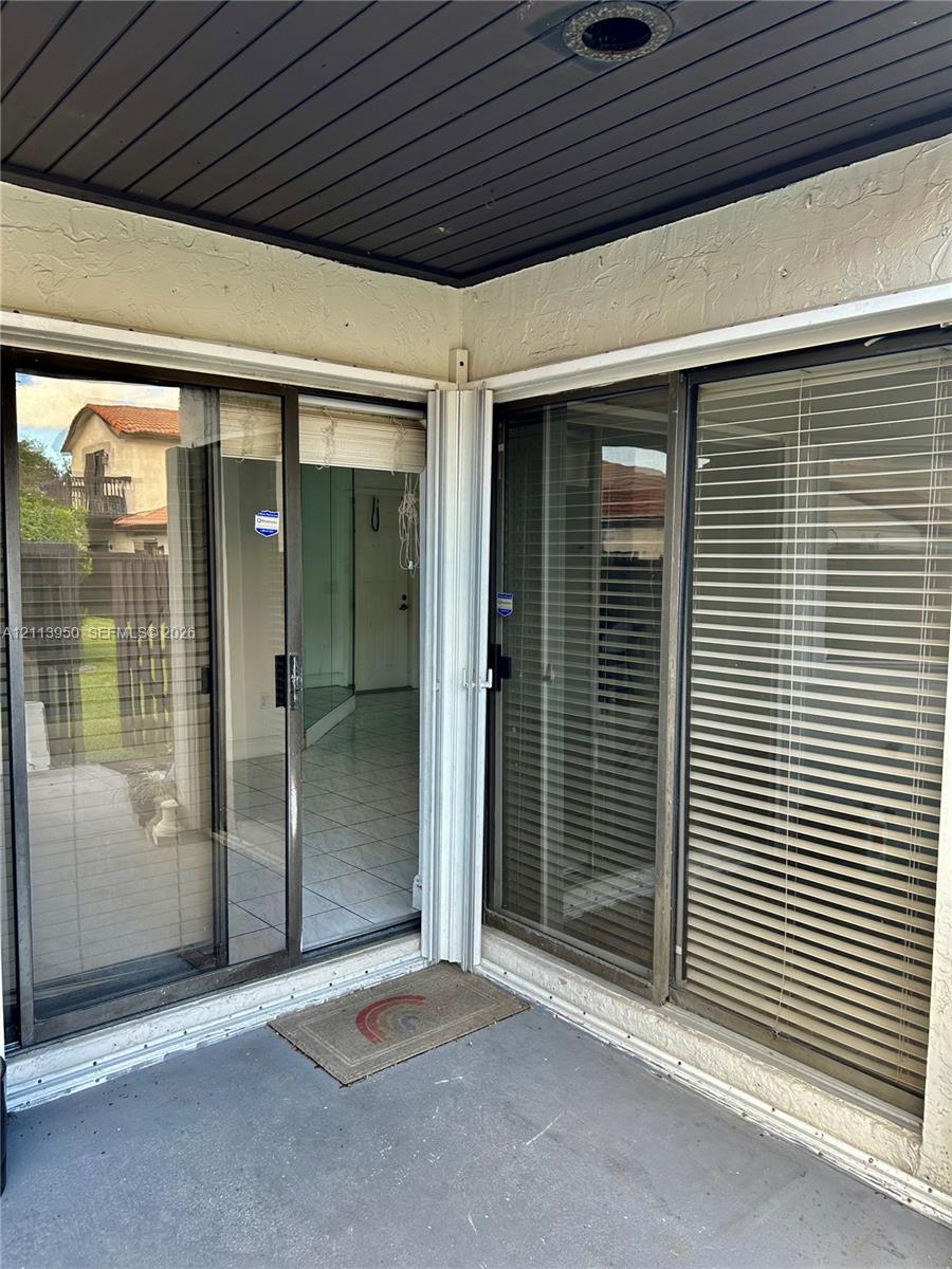 Covered exterior patio featuring dual glass sliding door panels and tile flooring