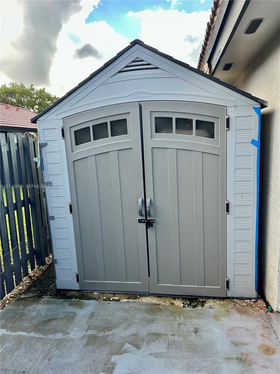Outdoor storage structure featuring a gable roof, double doors with integrated window panels, and a low-maintenance composite exterior