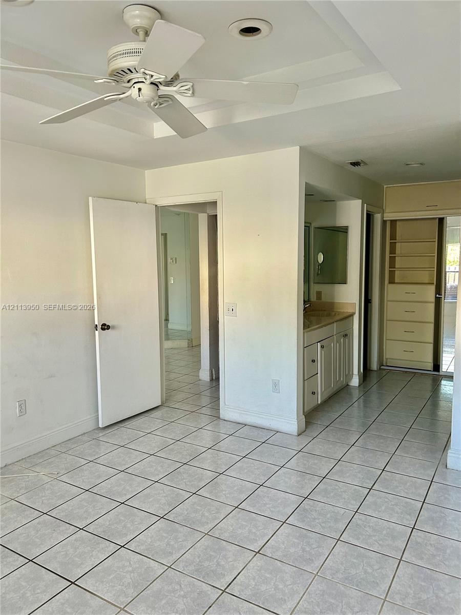 Tiled flooring, ceiling fan, vanity with cabinetry, and built-in shelving unit Tiled flooring, ceiling fan, vanity with cabinetry, and built-in shelving unit