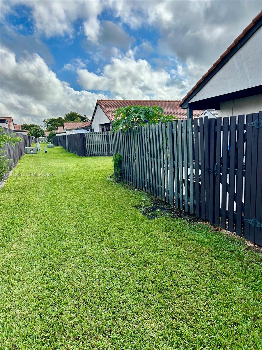 Exterior yard featuring a sprawling grass lawn and a full-height perimeter wood privacy fence