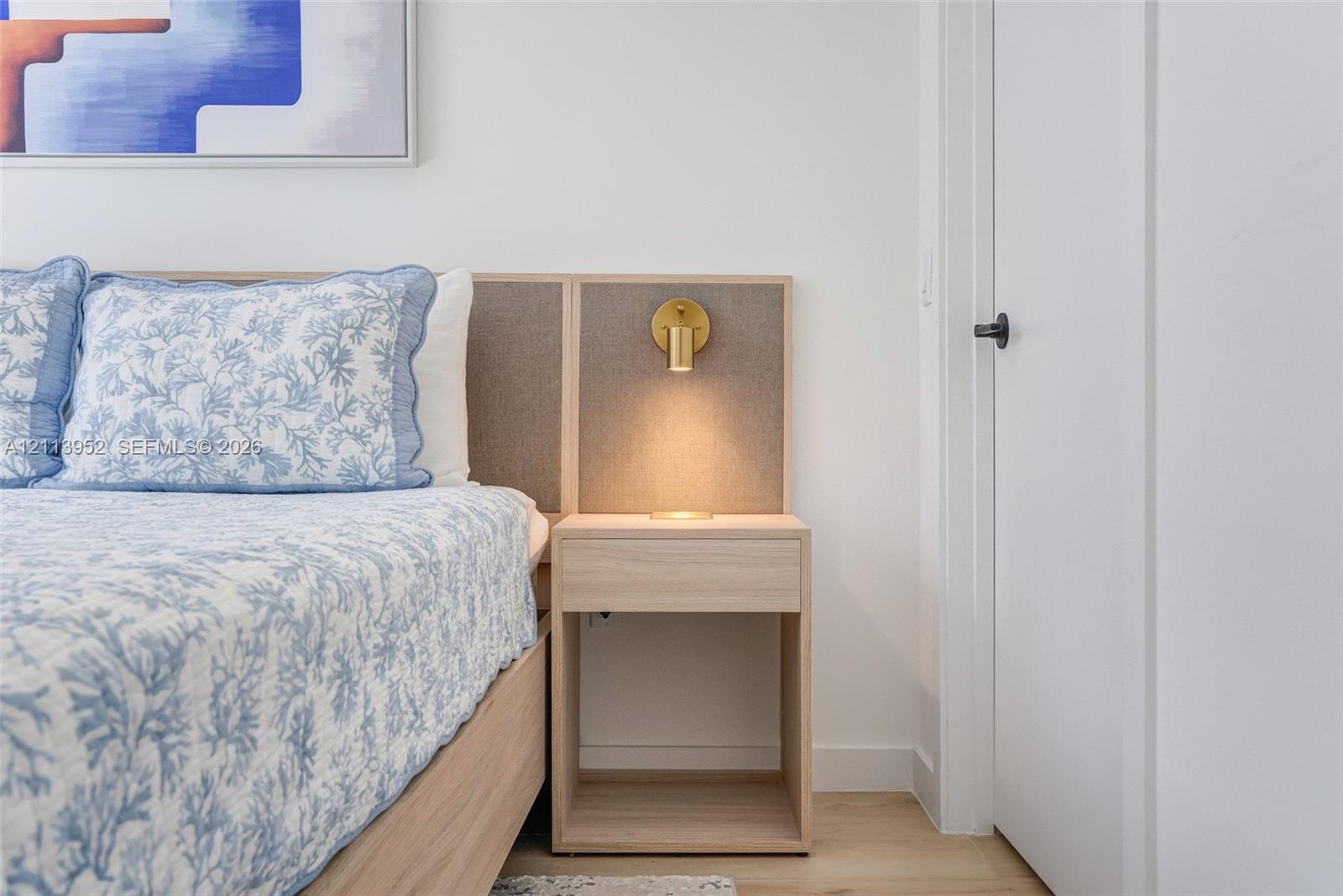 Custom built-in headboard featuring integrated light-wood-finish cabinetry and a brass wall-mounted light fixture
