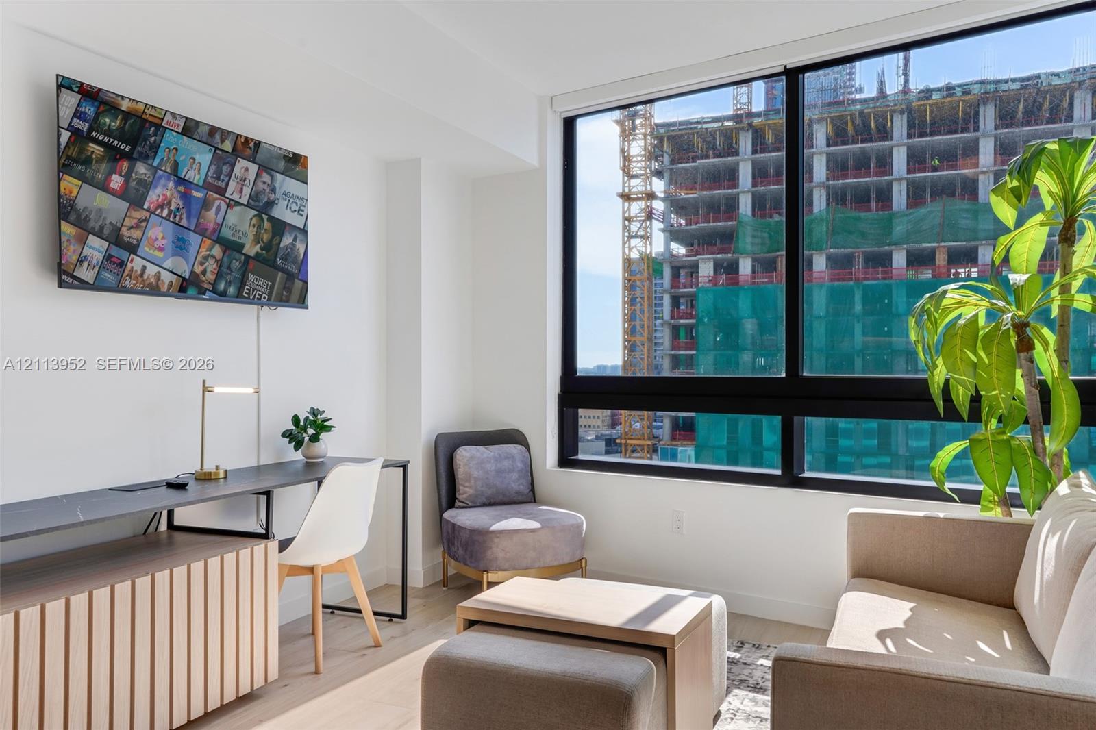 Floor-to-ceiling windows with black frames, wood-finish flooring, and crisp white walls