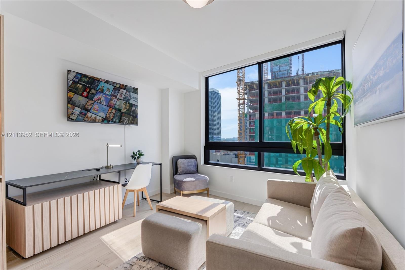 Floor-to-ceiling windows, wood-finish flooring, and crisp white walls