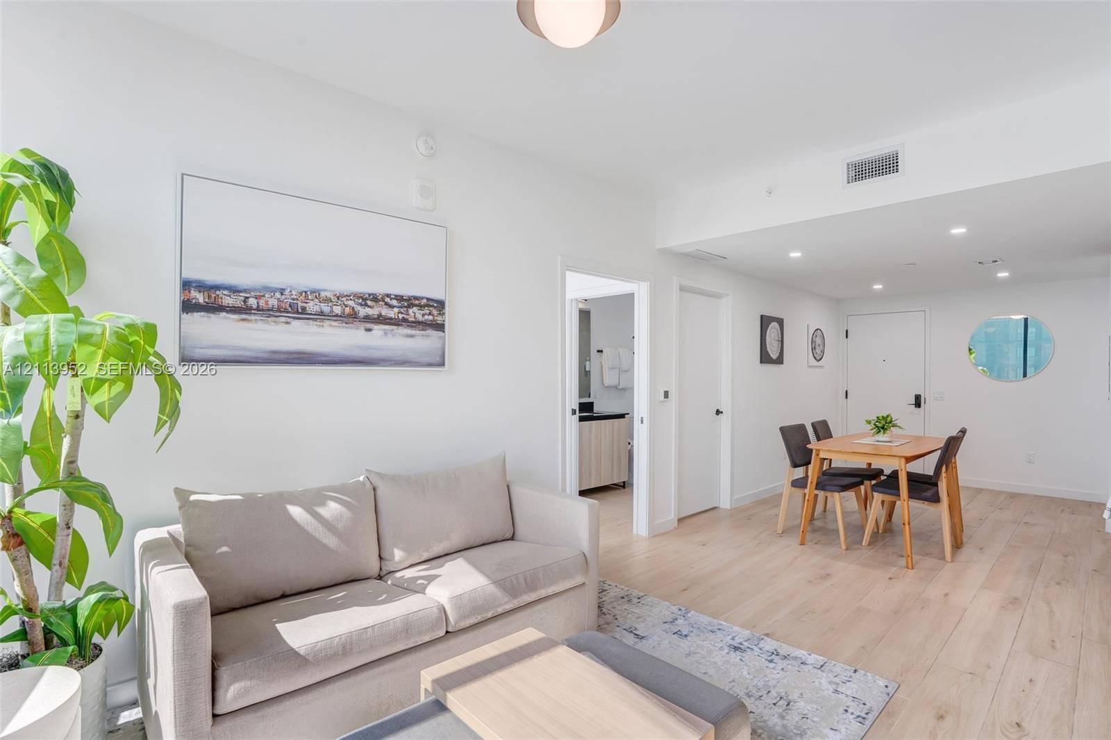 Open-concept interior featuring light wood-finish flooring, recessed lighting, and a neutral color palette