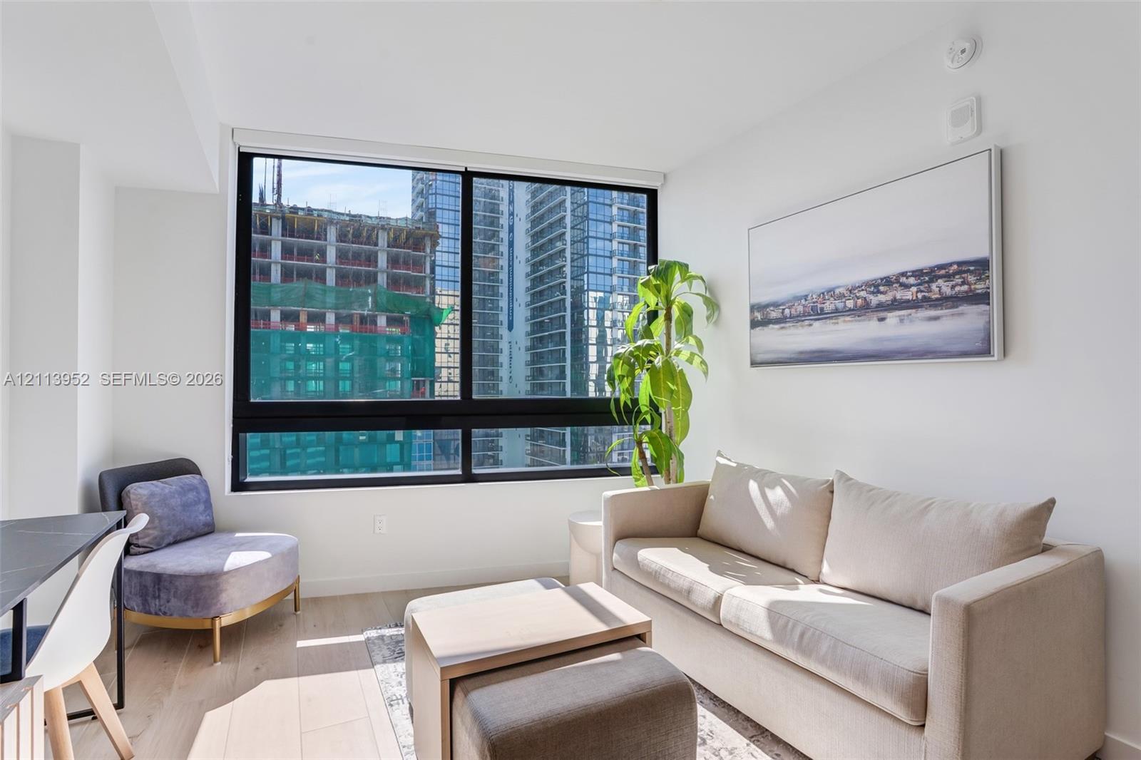 Floor-to-ceiling black-framed windows, wood-finish flooring, and crisp neutral wall finish