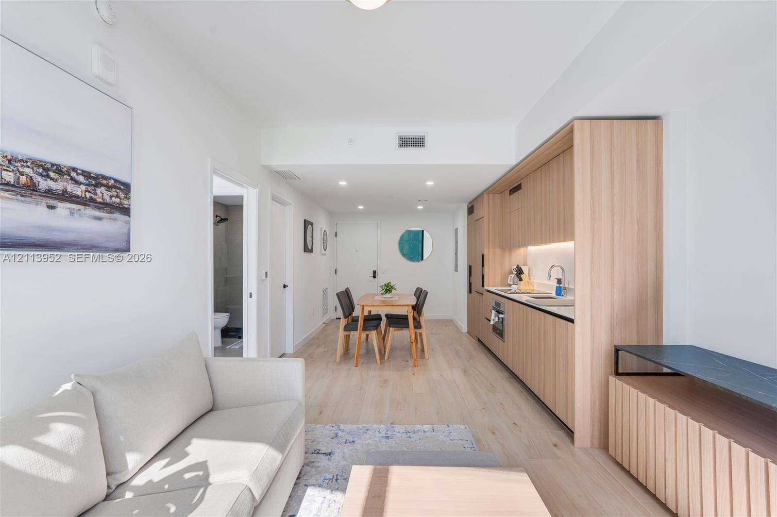Kitchen featuring light wood-finish cabinetry, recessed lighting, integrated appliances, and light-toned wood-finish flooring