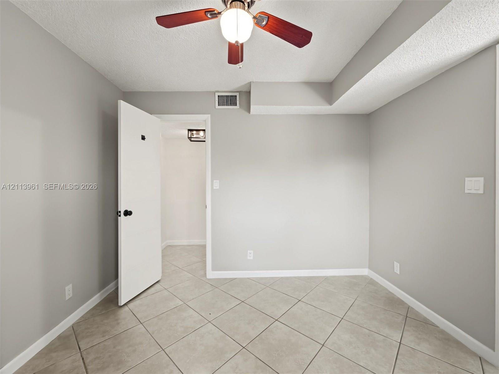 Room featuring neutral wall paint, diagonal-set ceramic tile flooring, and a ceiling fan with integrated lighting