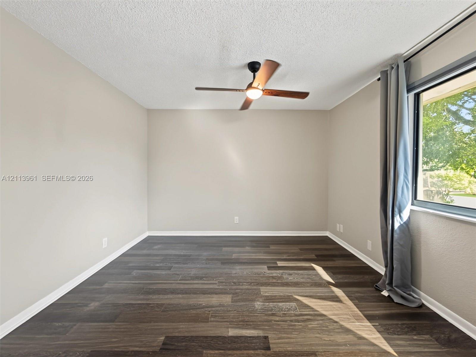 Neutral-toned walls, wood-finish flooring, and a ceiling-mounted fan with integrated lighting