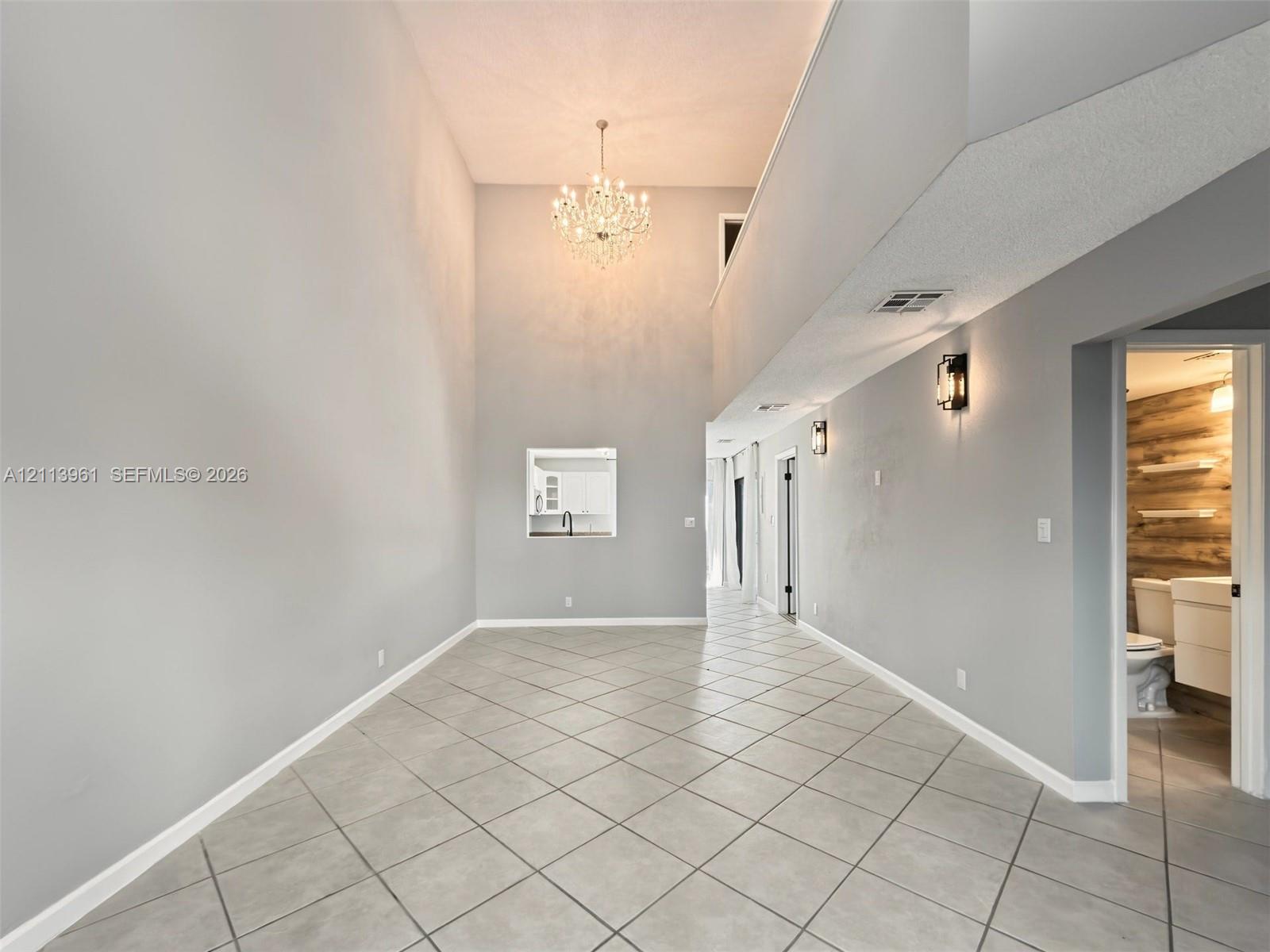 Vaulted ceilings, large-format tile flooring laid on the diagonal, multi-tiered crystal chandelier, recessed wall niche, and matching matte black wall-mounted fixtures Vaulted ceilings, large-format tile flooring laid on the diagonal, multi-tiered crystal chandelier, recessed wall niche, and matching matte black wall-mounted fixtures