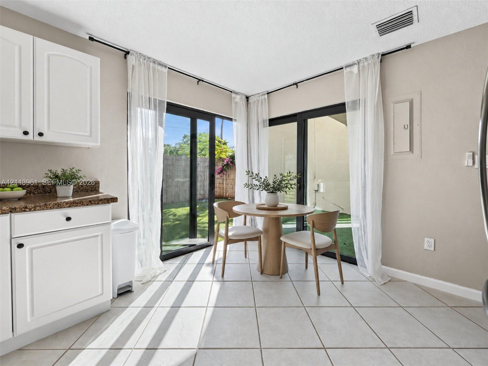 White cabinetry, stone-finish countertops, tile flooring, and floor-to-ceiling sliding glass doors