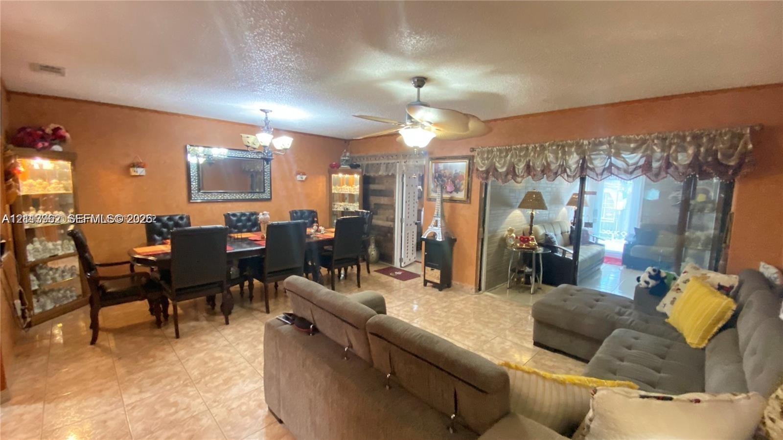 Open-concept interior featuring light-toned tile flooring, recessed lighting, dual ceiling fans, and sliding glass doors with overhead valance trim Open-concept interior featuring light-toned tile flooring, recessed lighting, dual ceiling fans, and sliding glass doors with overhead valance trim