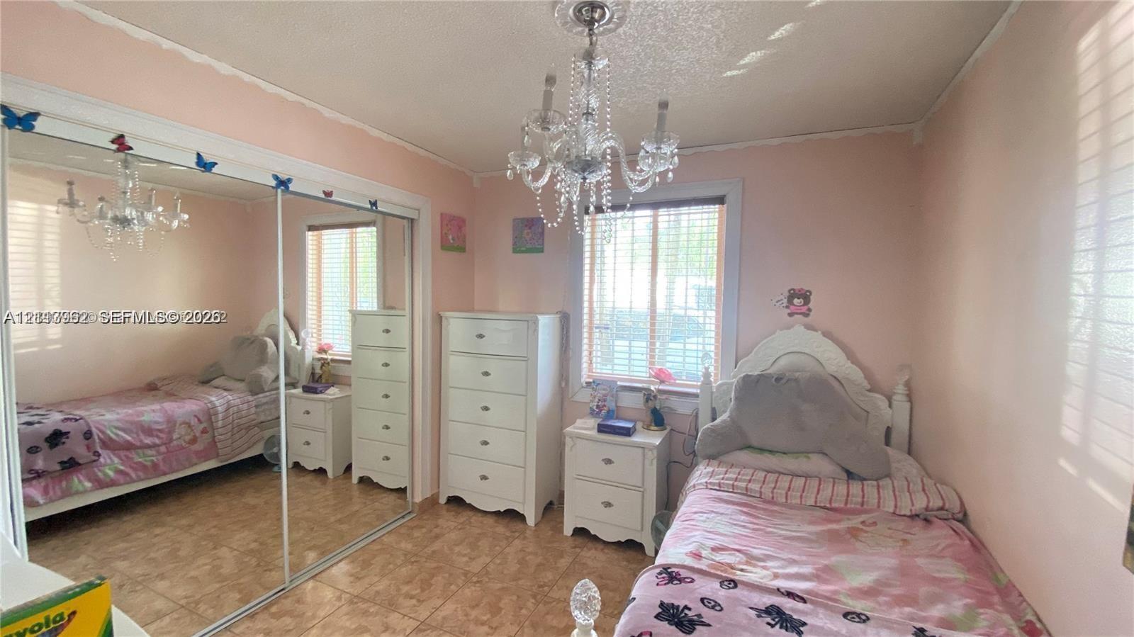 Room interior featuring tile flooring, a large sliding glass-door closet, and an ornate crystal-style chandelier Room interior featuring tile flooring, a large sliding glass-door closet, and an ornate crystal-style chandelier