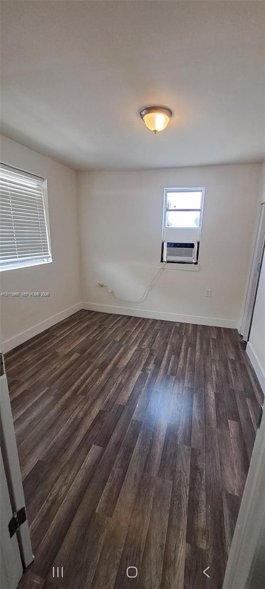 Room featuring wood-finish flooring, two windows with horizontal blinds, and a dome-style flush mount ceiling light fixture Room featuring wood-finish flooring, two windows with horizontal blinds, and a dome-style flush mount ceiling light fixture