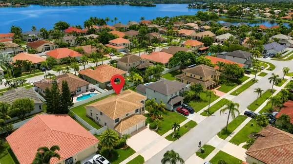 Aerial perspective showcasing a residential property with a tiled roof, multi-car garage, concrete driveway, and a private swimming pool enclosed by privacy fencing Aerial perspective showcasing a residential property with a tiled roof, multi-car garage, concrete driveway, and a private swimming pool enclosed by privacy fencing