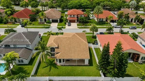 Aerial view of property featuring a multi-pitched clay tile roof, expansive rear lawn, white vinyl fencing, and covered patio Aerial view of property featuring a multi-pitched clay tile roof, expansive rear lawn, white vinyl fencing, and covered patio